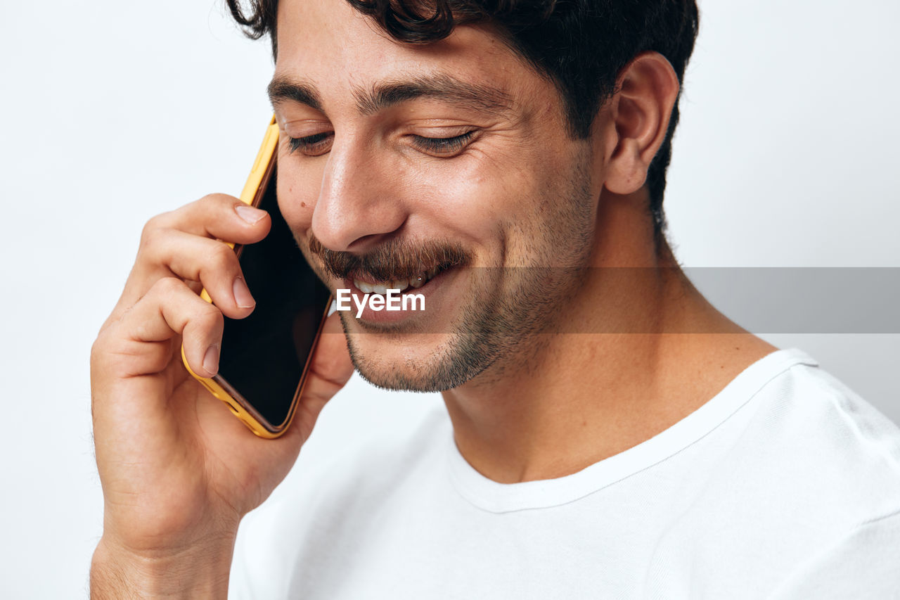 portrait of man using mobile phone against white background