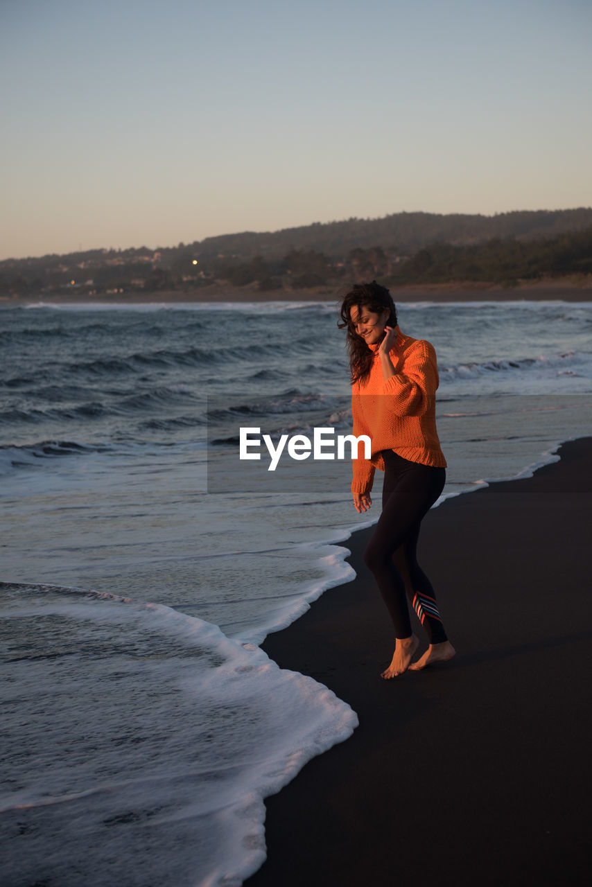 Smiling woman dips her feet in surf