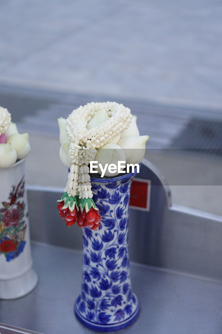 CLOSE-UP OF WHITE ROSE ON TABLE AGAINST WALL