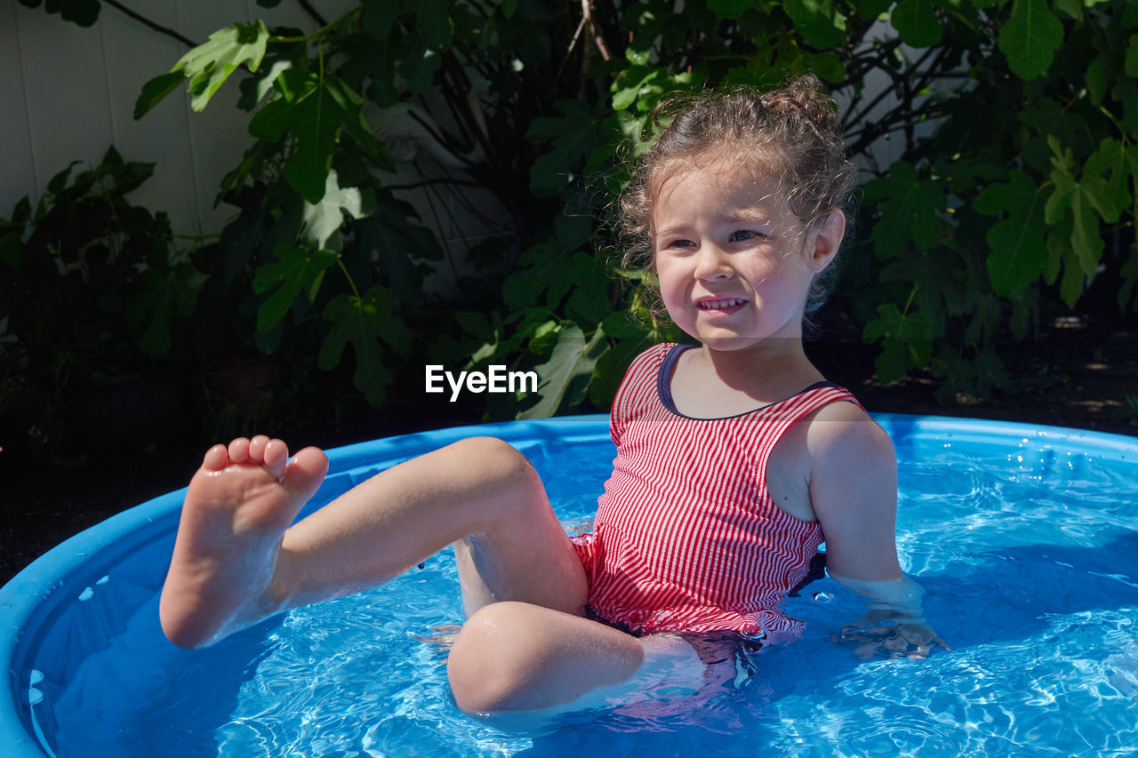 Cute toddler playing in the water basin in the backyard