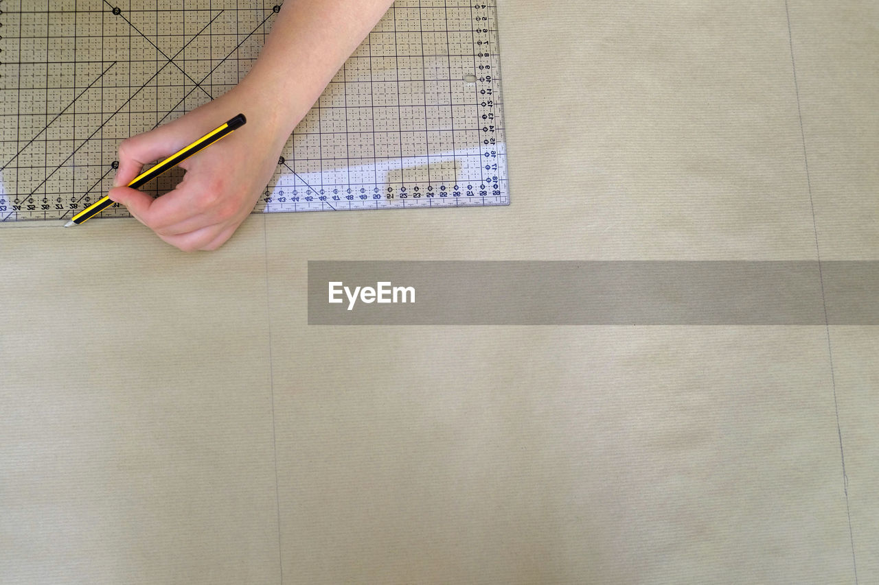 Cropped hands of woman drawing on paper at desk