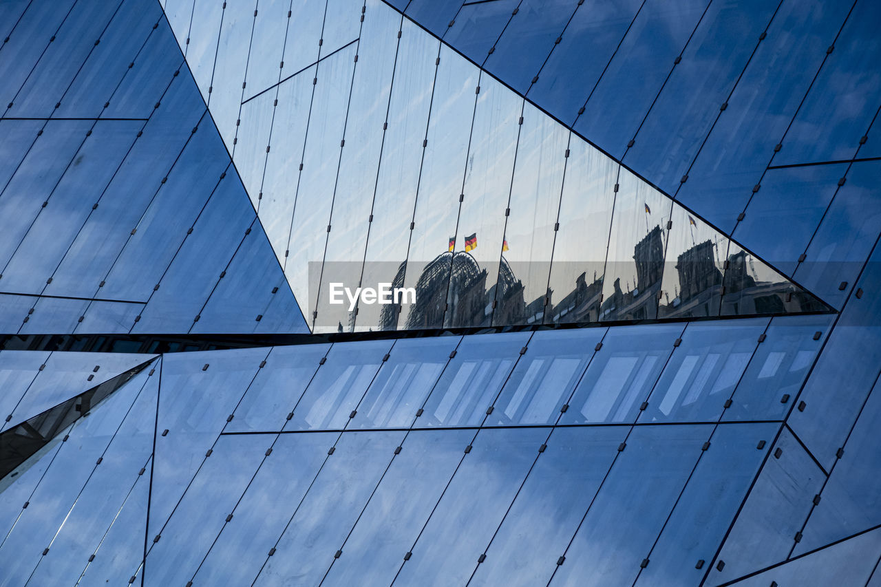 Low angle view of glass building against blue sky