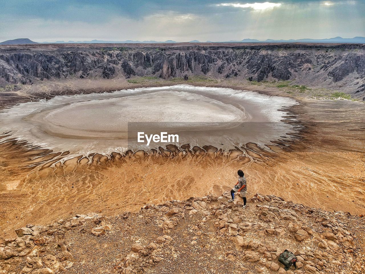 High angle view of mid adult man standing on arid landscape against sky