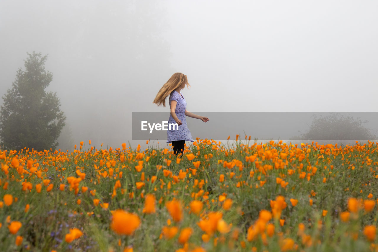 Woman standing on field against sky