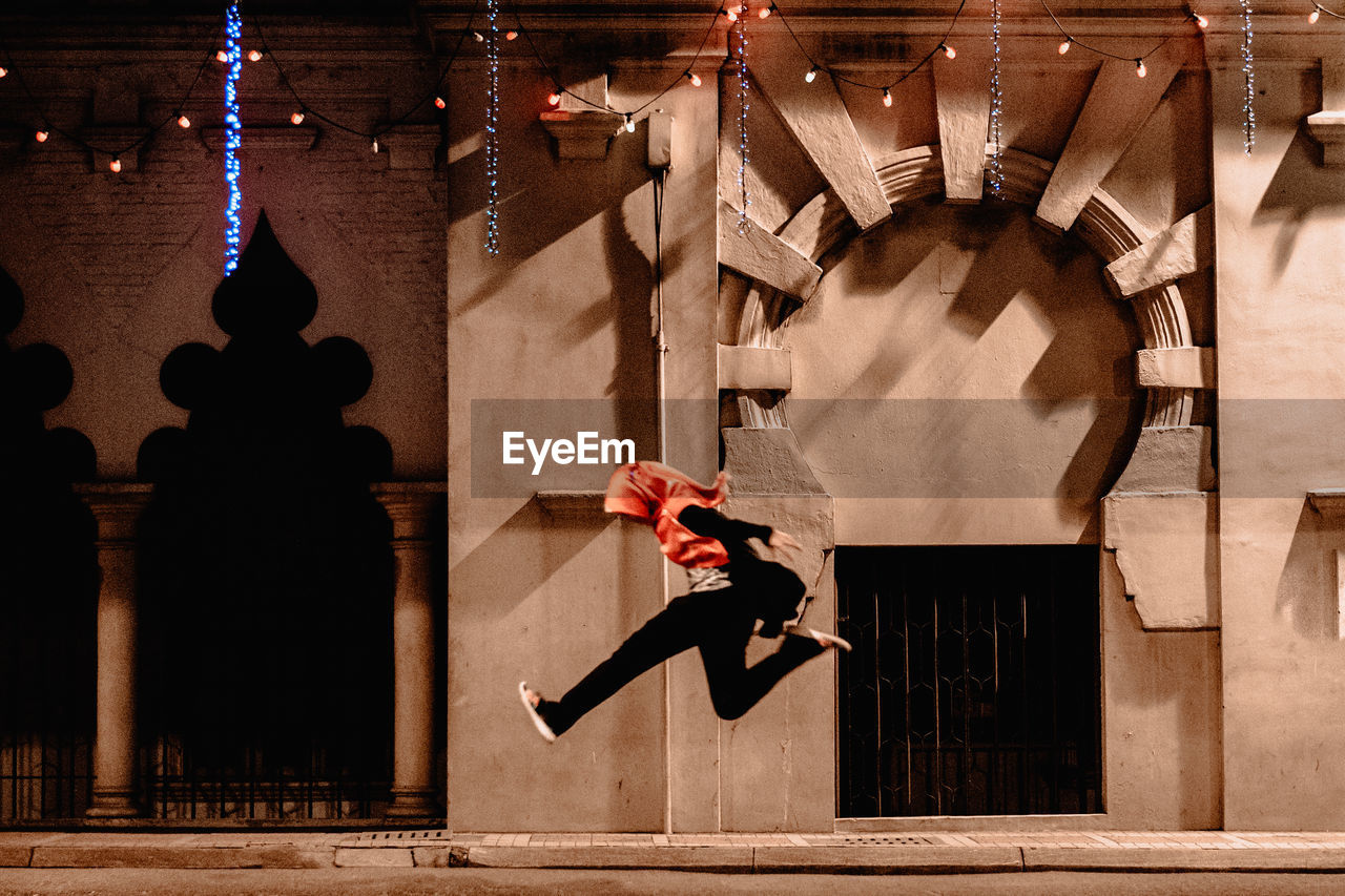 A girl in hijab jumping along the city street at night