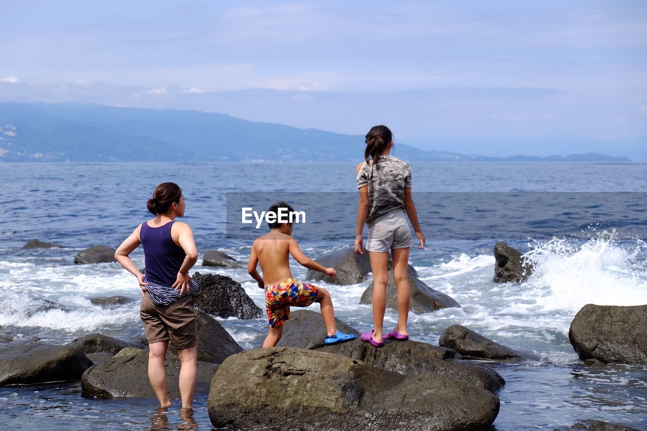 Rear view of family standing on shore against sea