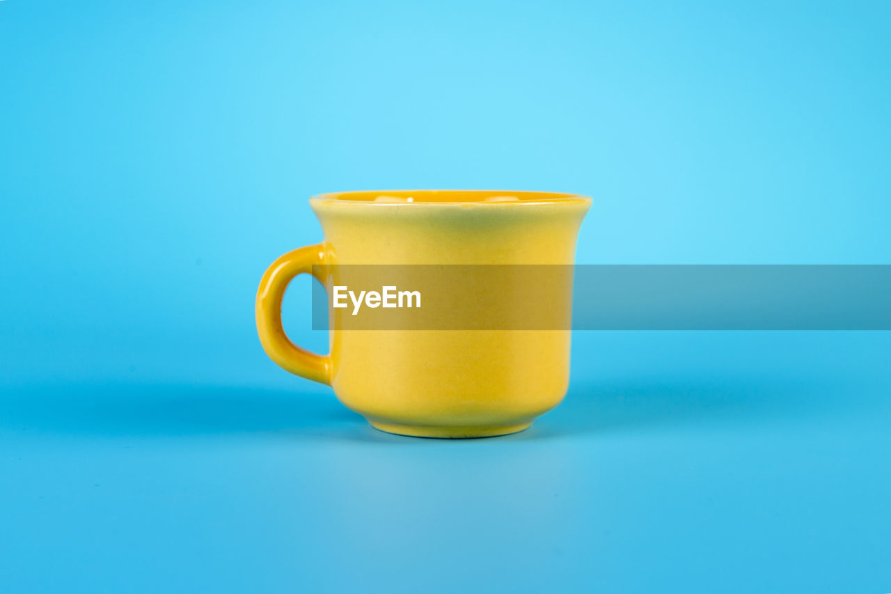 CLOSE-UP OF CUP OF COFFEE AGAINST BLUE BACKGROUND