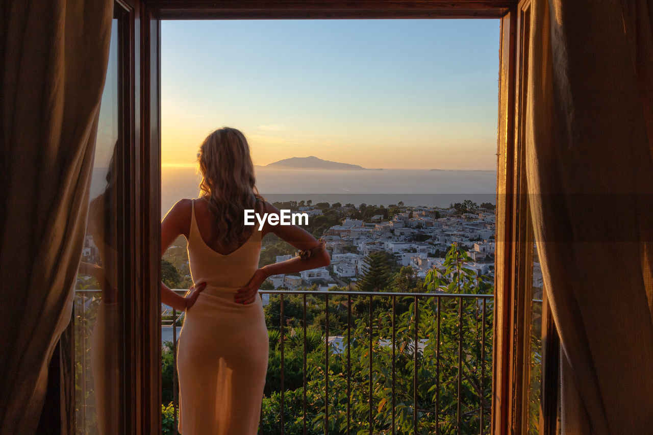 Rear view of woman standing in balcony against sky