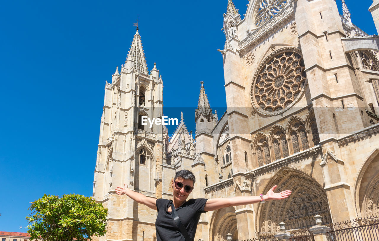 Woman with open arms in front of the cathedral of leon in spain