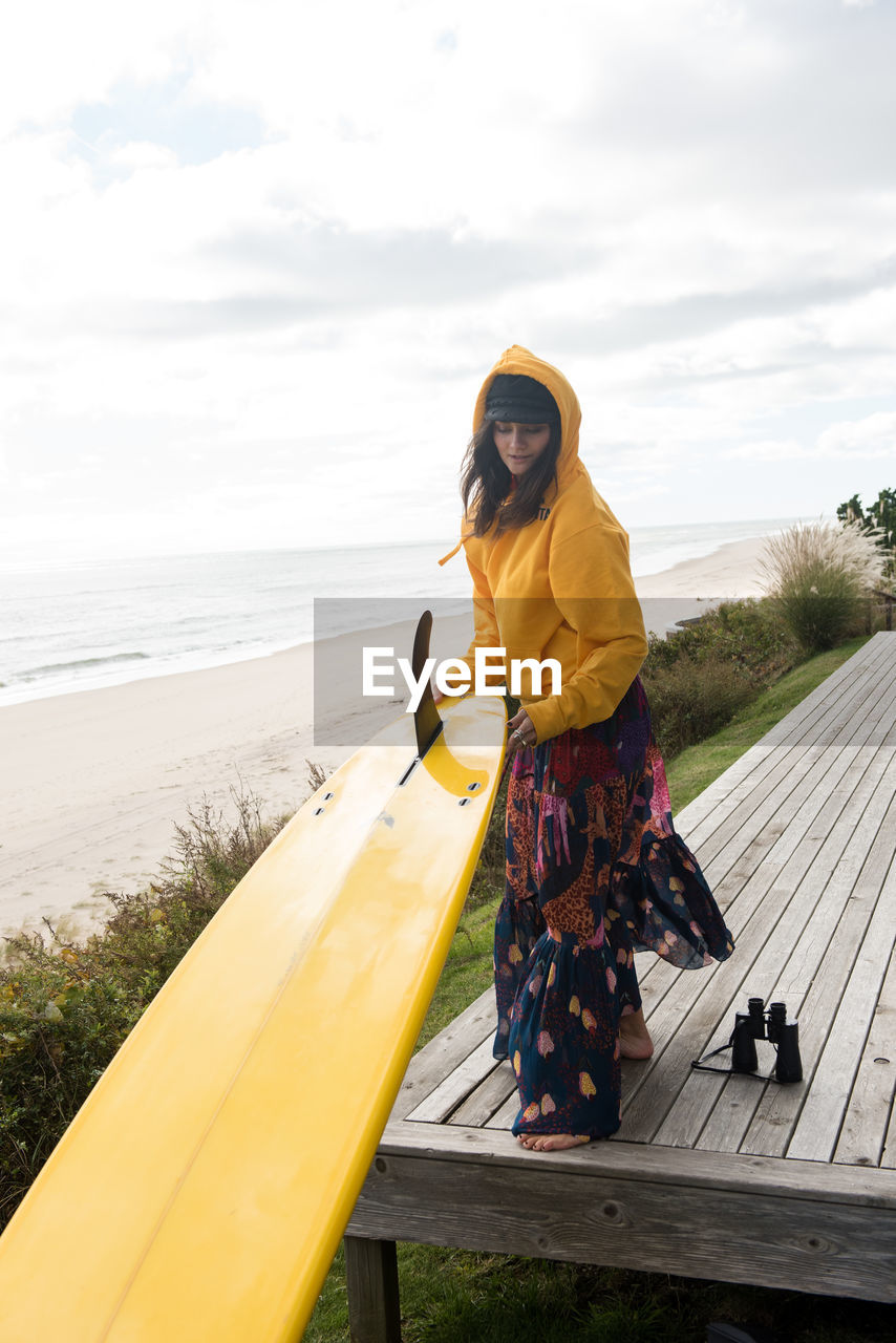 Female surfer prepares her surfboard for adventure