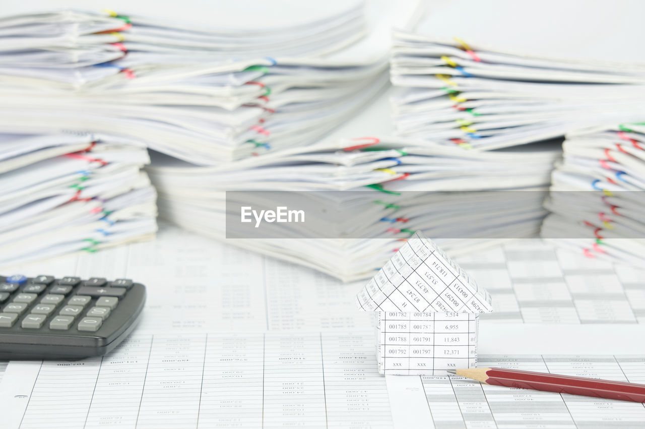 Close-up of model house with pencil and calculator on financial documents