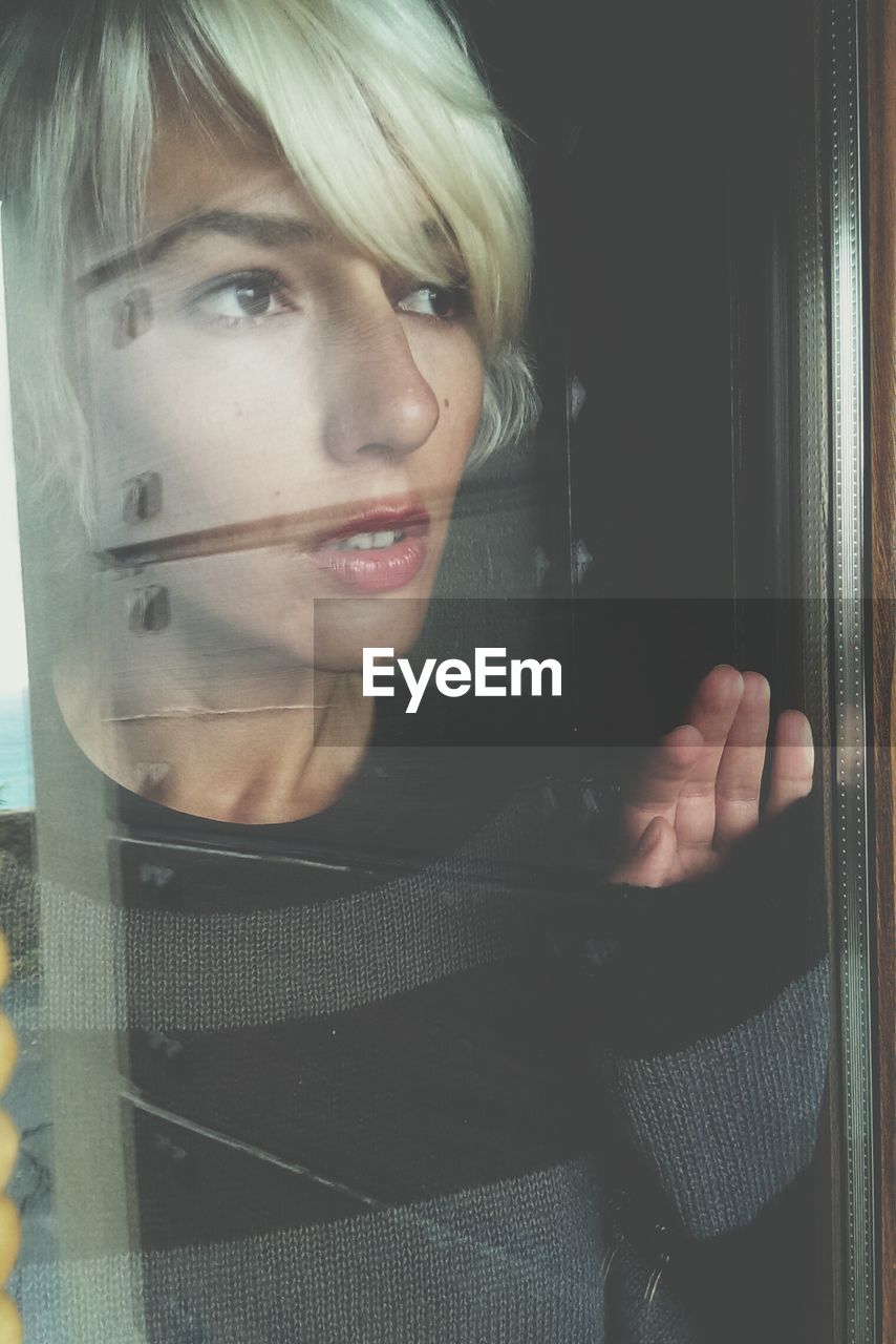 Close-up of thoughtful young woman looking through window