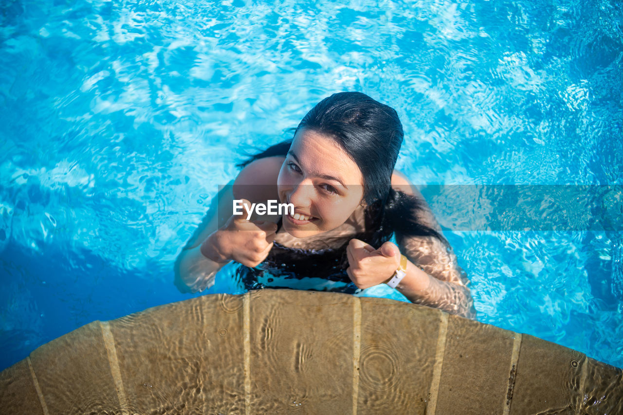 portrait of young woman sitting on swimming pool
