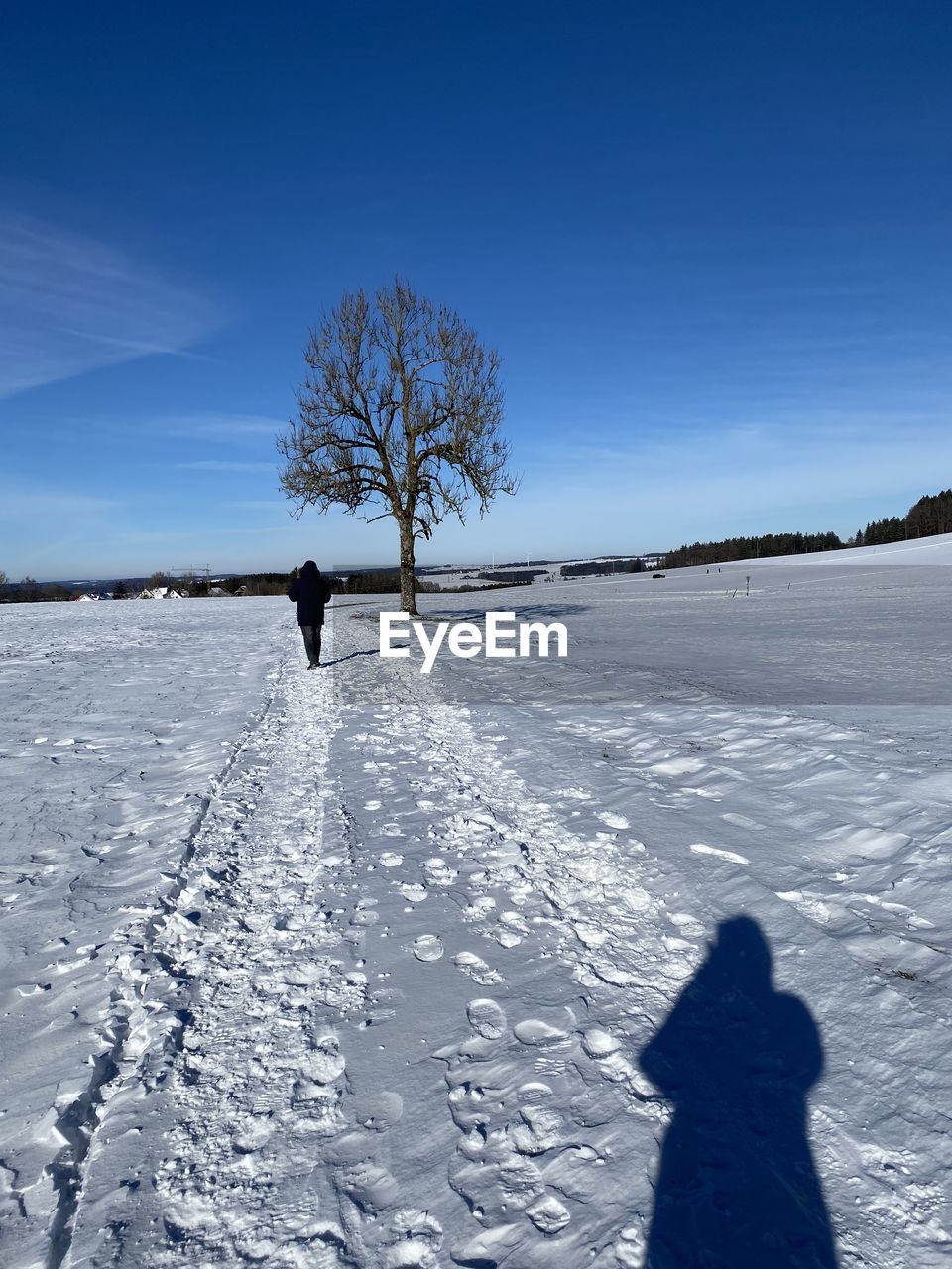 Silhouette person on snow covered field against sky