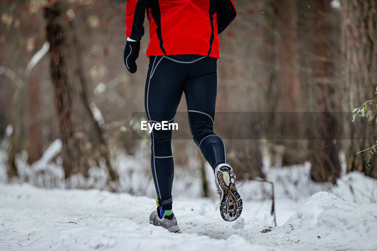 Legs male runner run race in winter forest