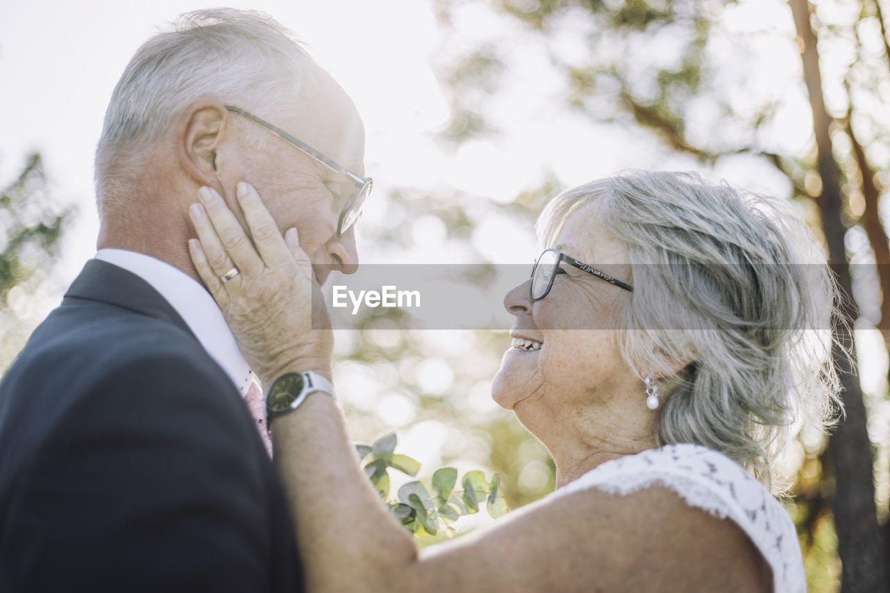 Smiling affectionate senior bride touching groom's cheek