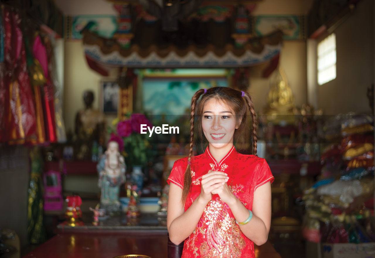 Smiling young woman in traditional clothing standing at home