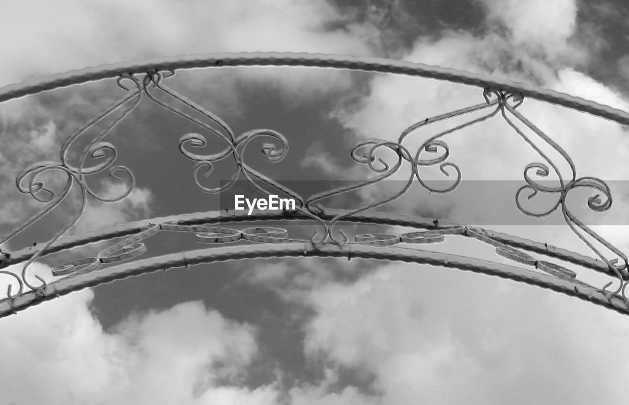 Low angle view of metal fence against sky