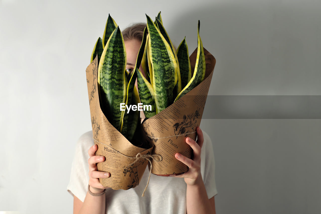 Young woman holds two succulet house plants - a new addition to her indoor garden