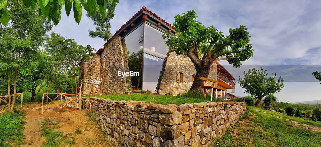 OLD RUIN AMIDST TREES ON FIELD AGAINST SKY