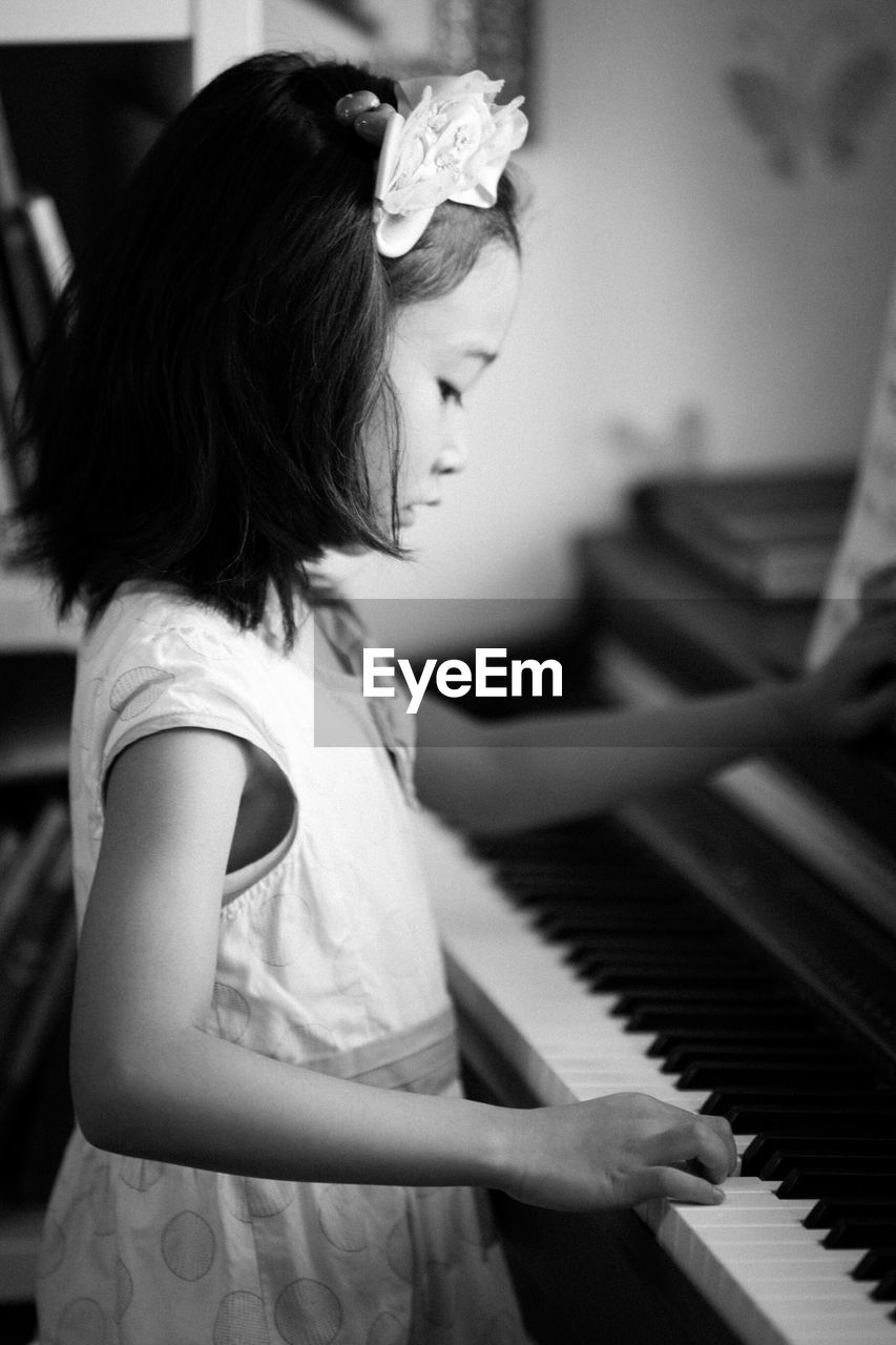 Side view of girl playing piano