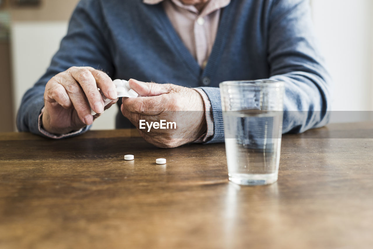 Hands of senior man taking tablets out of blister pack, close-up