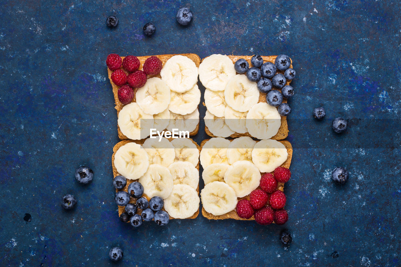 Healthy breakfast of sandwiches with peanut butter, banana and berries on a dark blue background. 