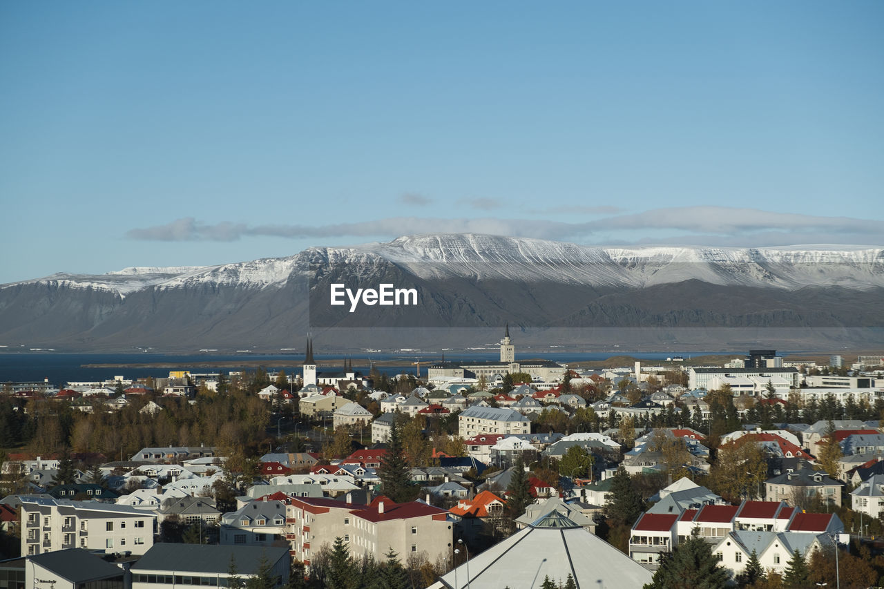 Aerial view of townscape and mountains against sky