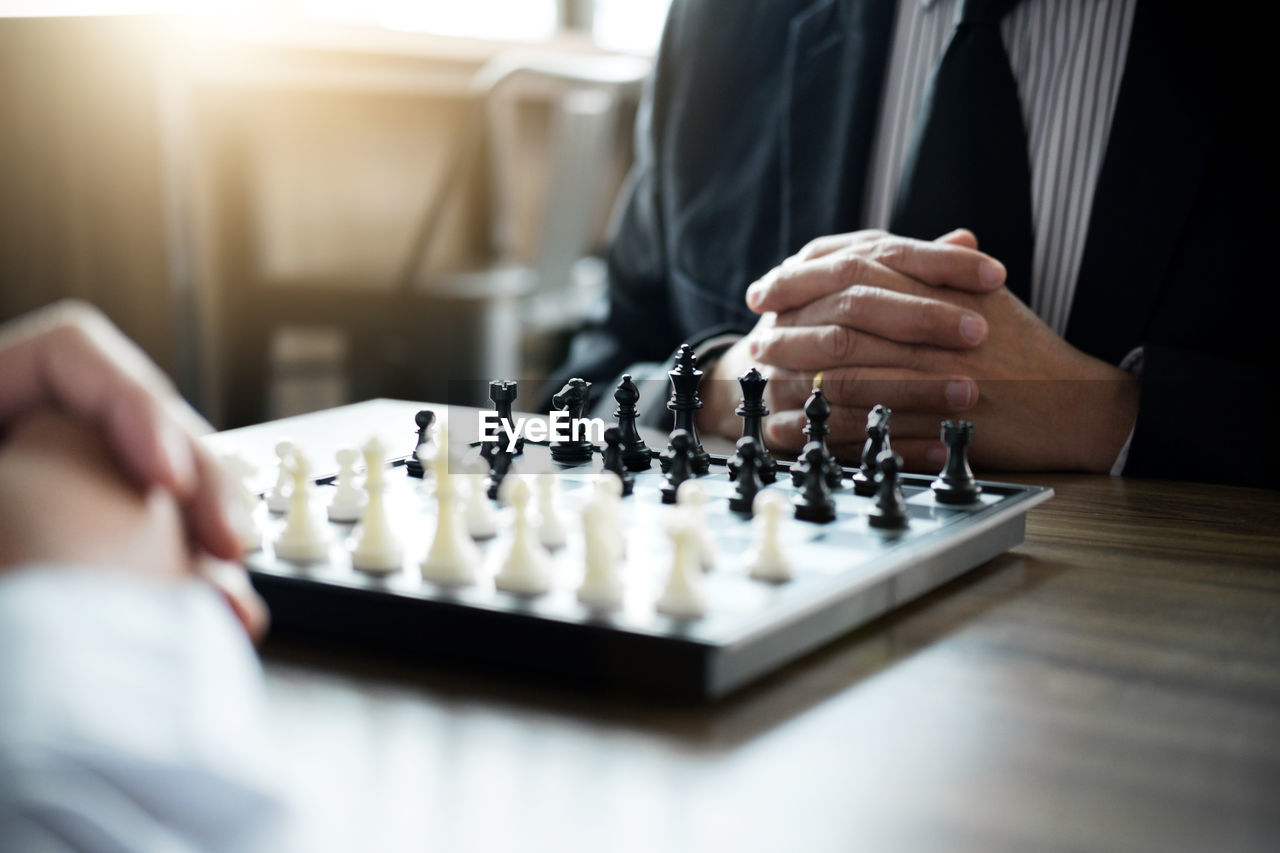 Business people playing chess at desk in office