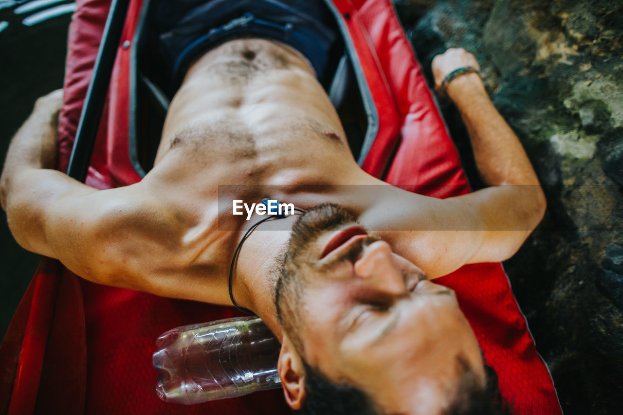 High angle view of shirtless man sleeping on kayak