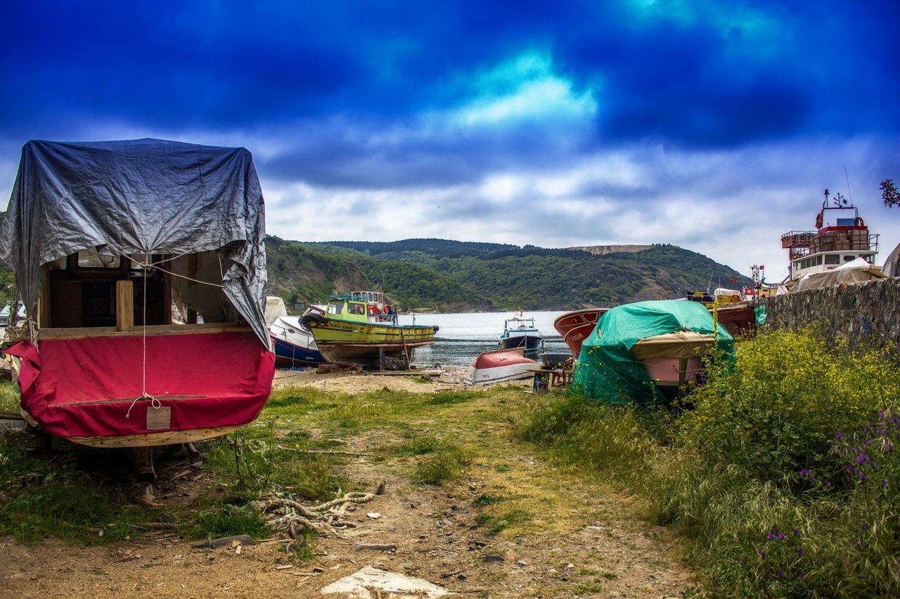 Loaded truck and boats at riverbank on cloudy day