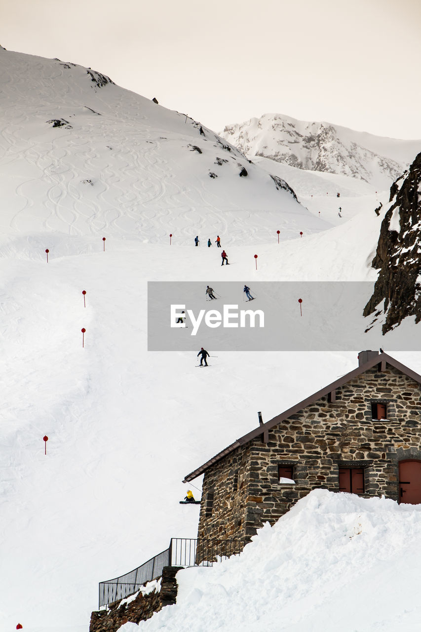 People skiing downhill on mountain against sky