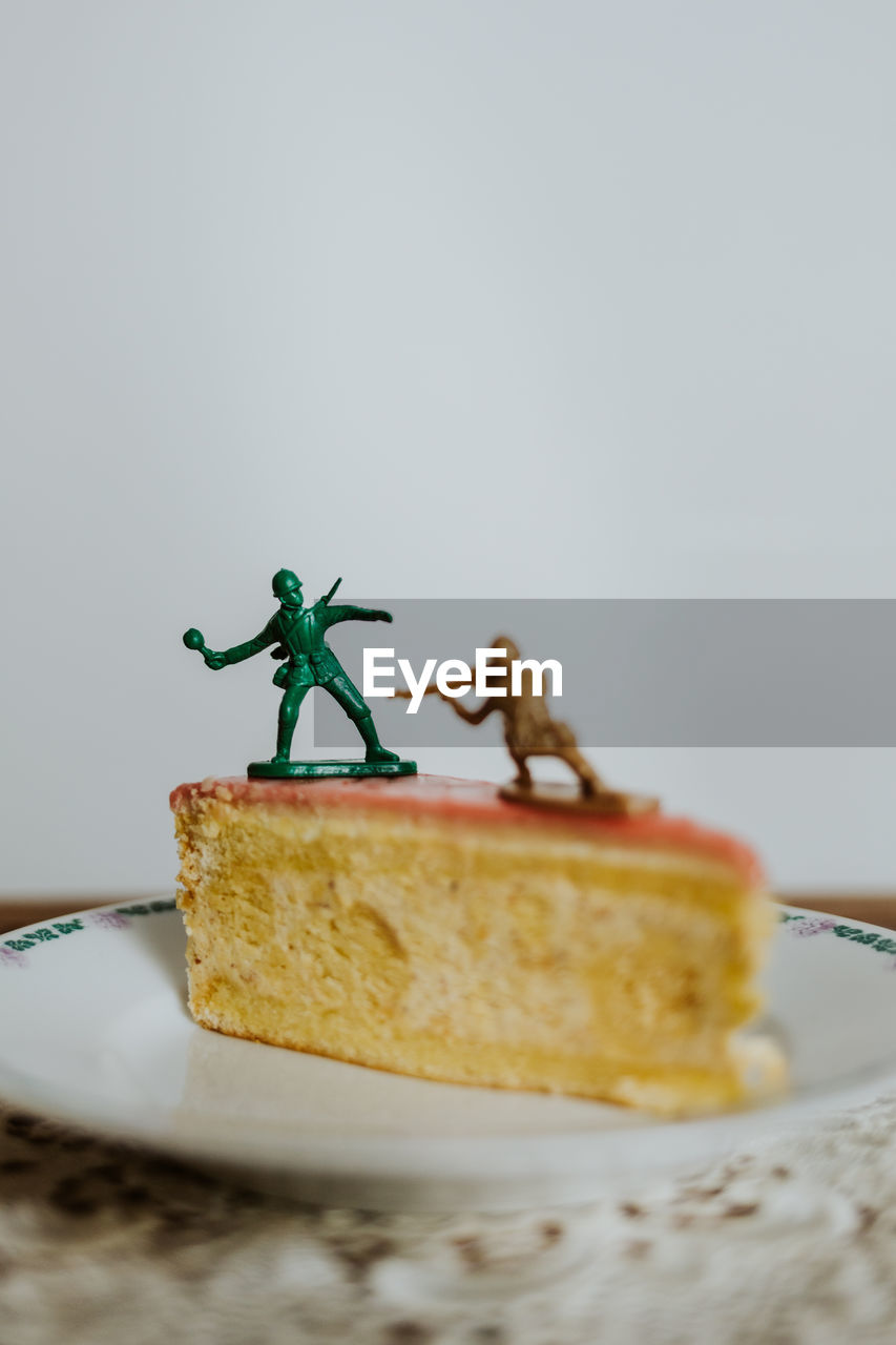 Two toy soldiers fighting on the top of a piece of cake about calories - close up white background