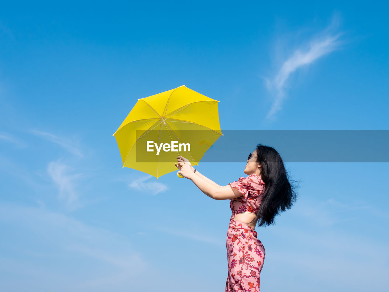 WOMAN HOLDING UMBRELLA AGAINST SKY