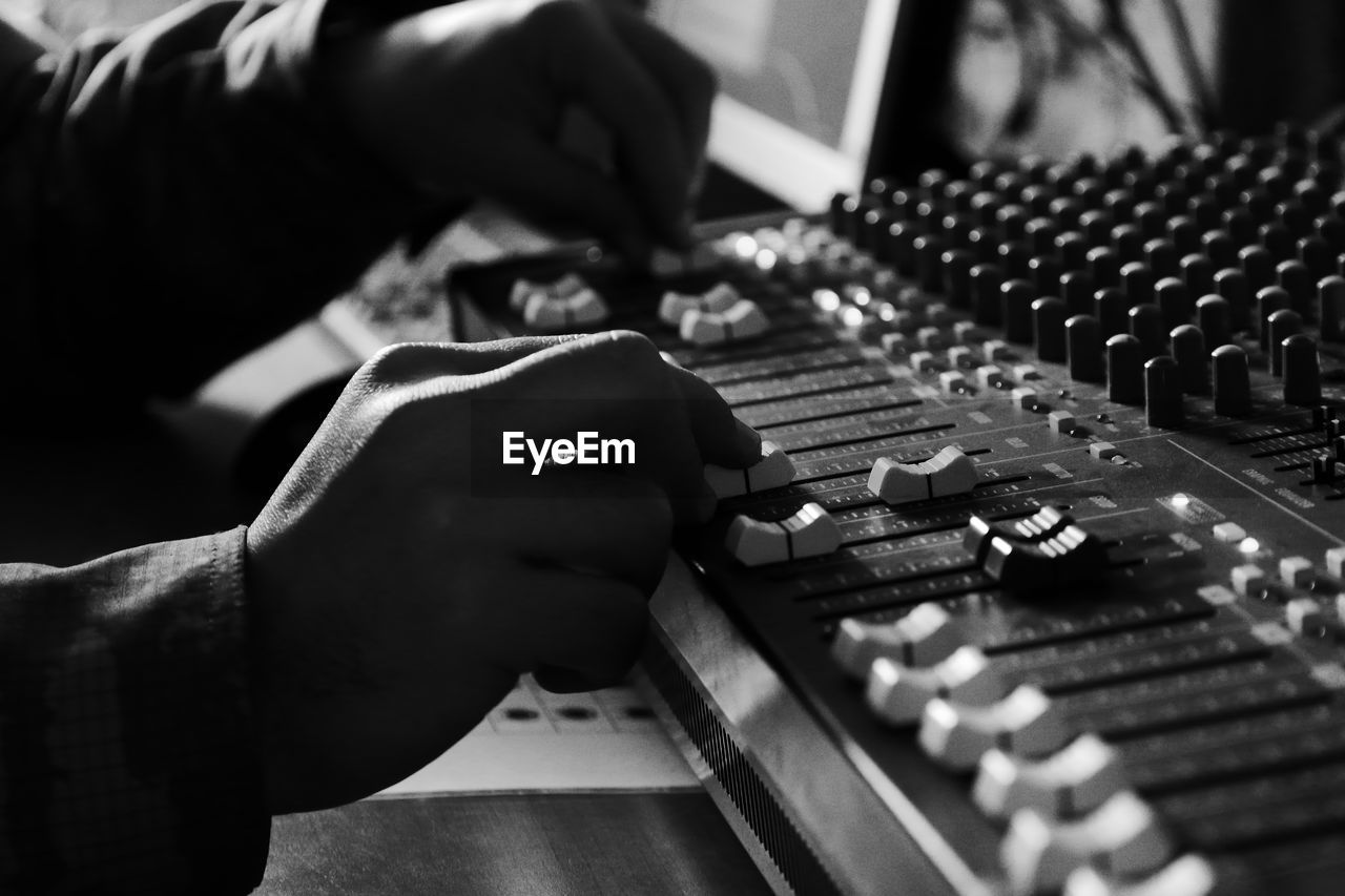 Cropped hands of man adjusting sound mixer knobs 