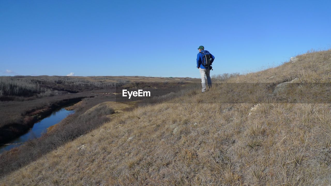 Rear view of man standing on field against sky