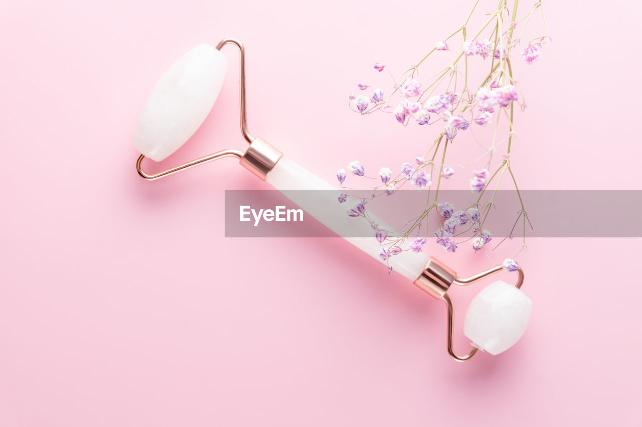 high angle view of magnifying glass and in-ear headphones on pink background