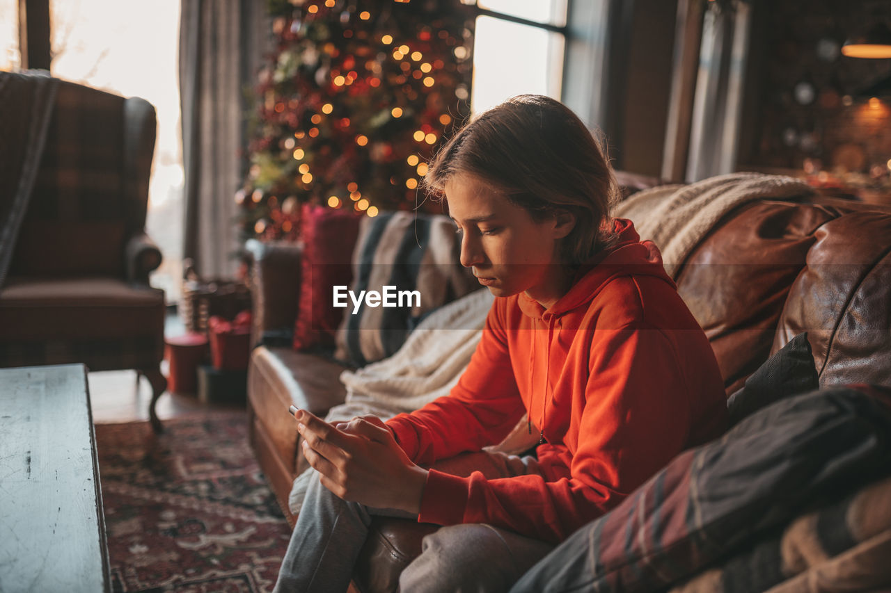 Portrait of candid authentic dreamer boy teenager in sadness depressing emotion at home xmas