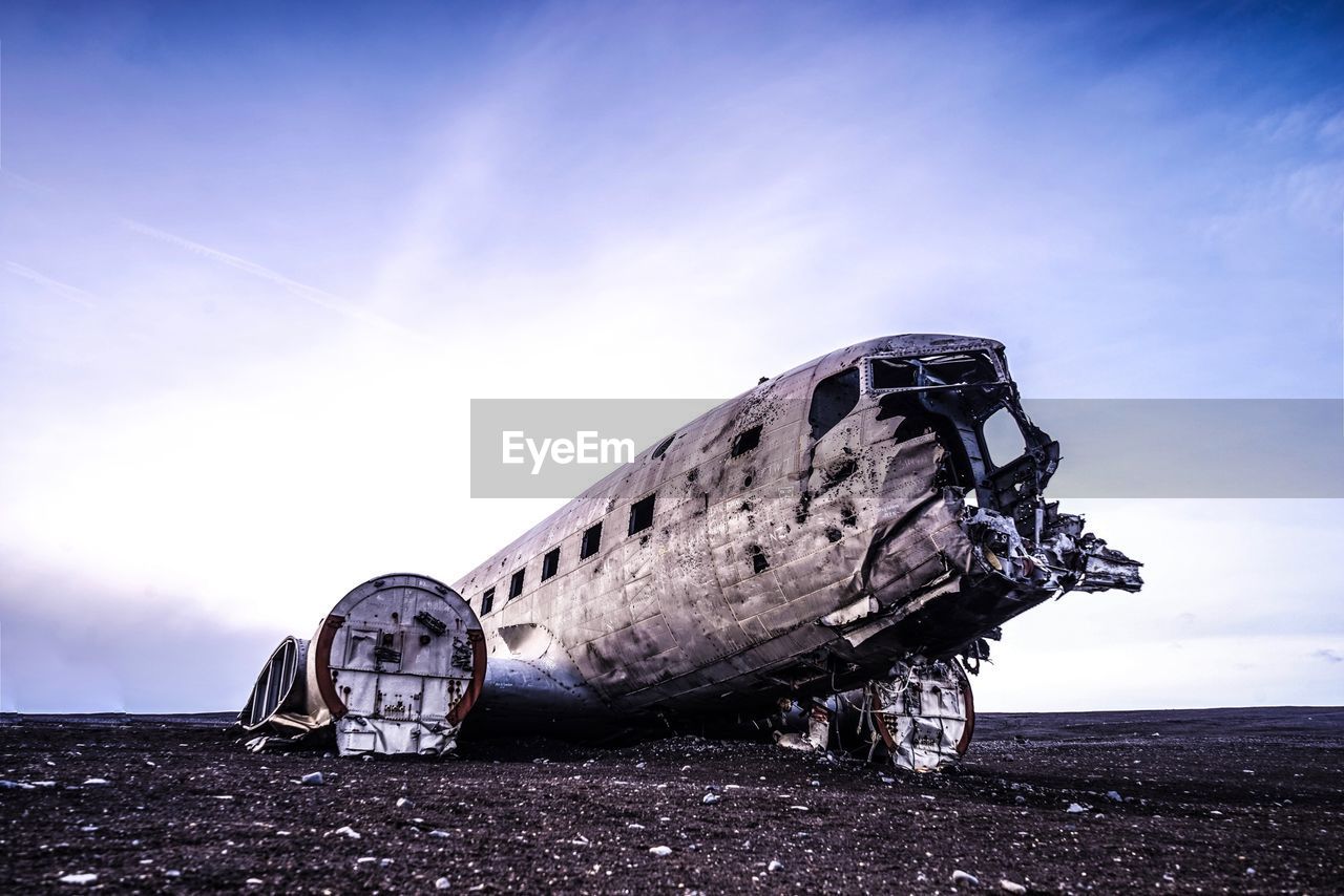 Abandoned airplane at beach against sky