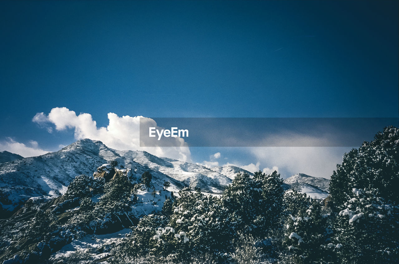 Scenic view of snowcapped mountains against blue sky