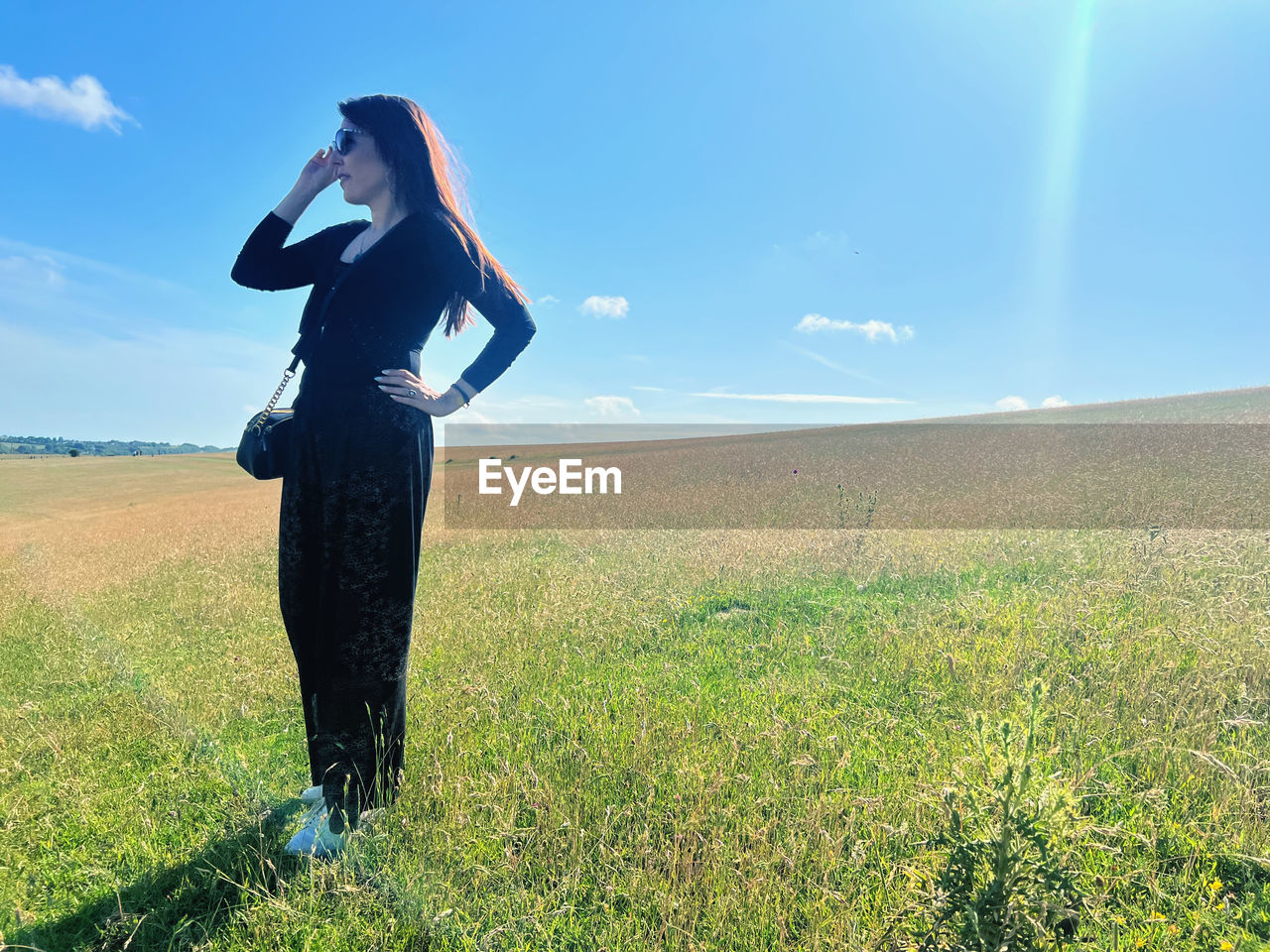one person, sky, adult, nature, grass, landscape, field, women, land, environment, plant, meadow, standing, grassland, sunlight, beauty in nature, rural scene, young adult, green, full length, blue, day, plain, scenics - nature, horizon, natural environment, female, horizon over land, person, outdoors, tranquility, lifestyles, clothing, cloud, leisure activity, tranquil scene, solitude, copy space, long hair, non-urban scene, sunny, fashion, hairstyle, summer, looking, emotion