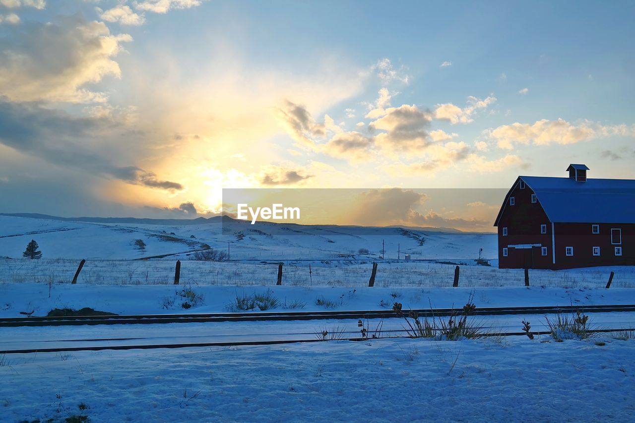 Houses on snow covered field against sky