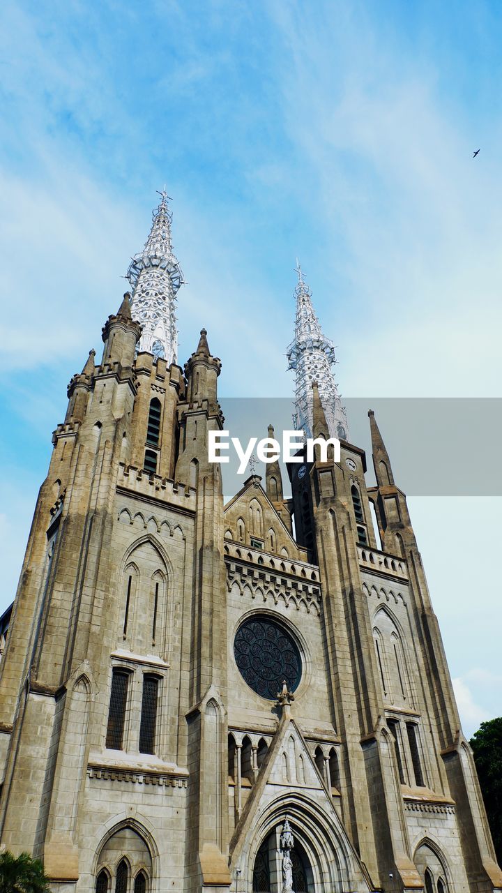 Low angle exterior architecture view of historical cathedral catholic church building against sky