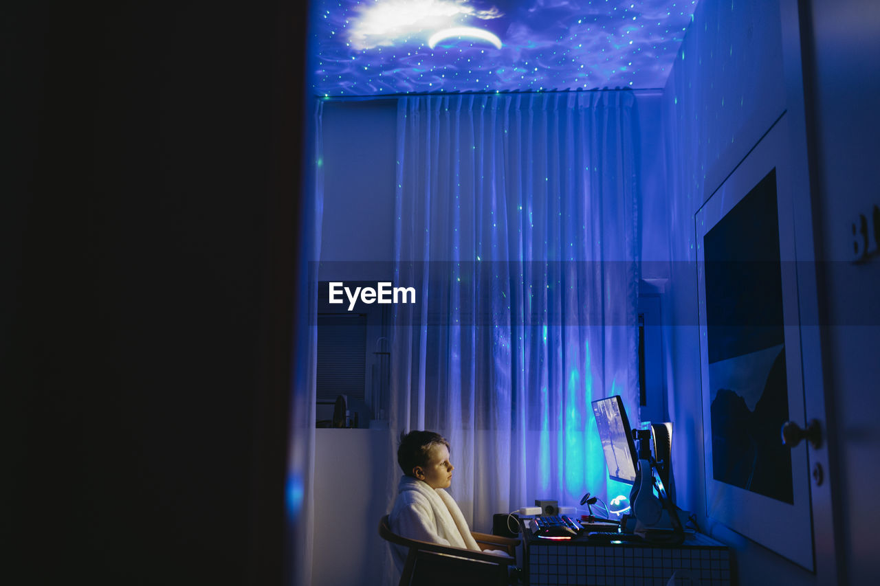 Boy at desk using computer at night