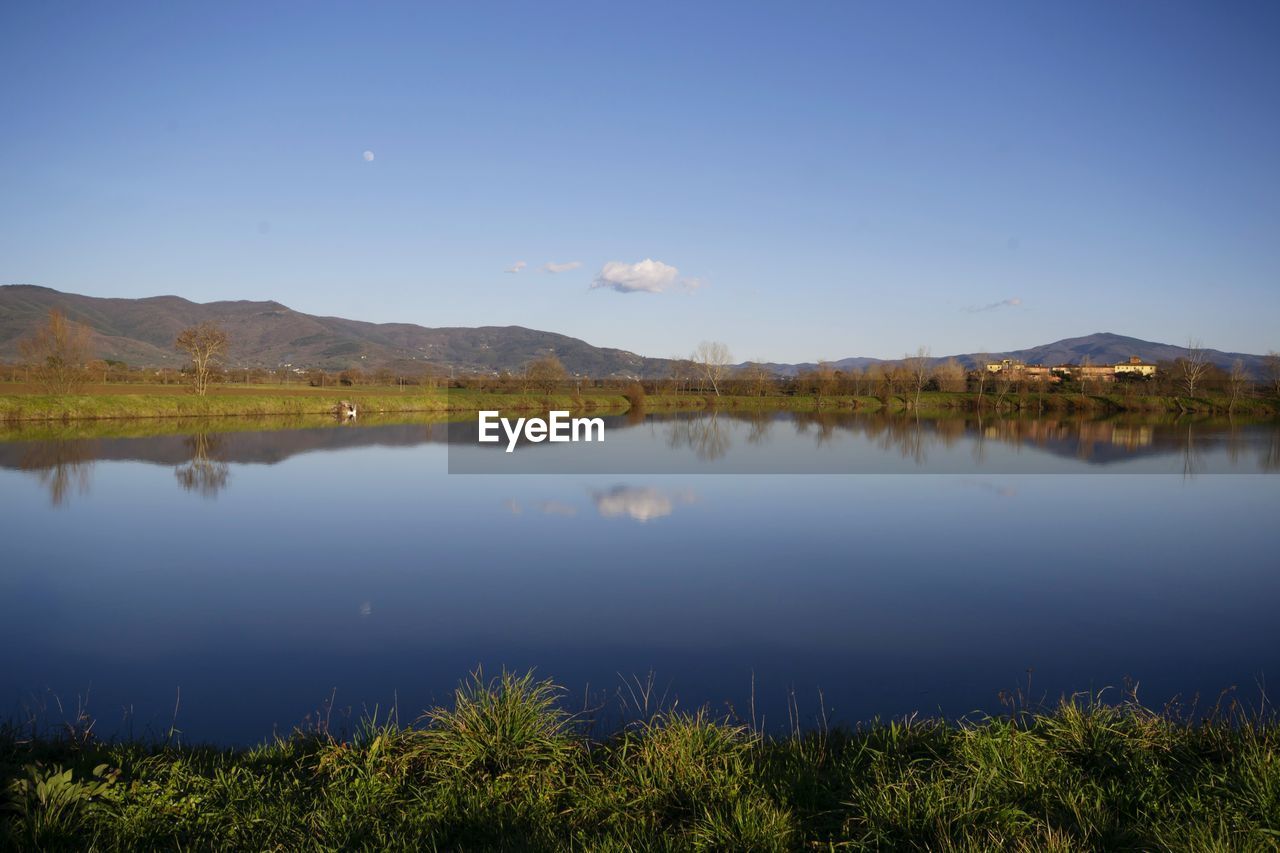 Scenic view of lake and mountains against blue sky