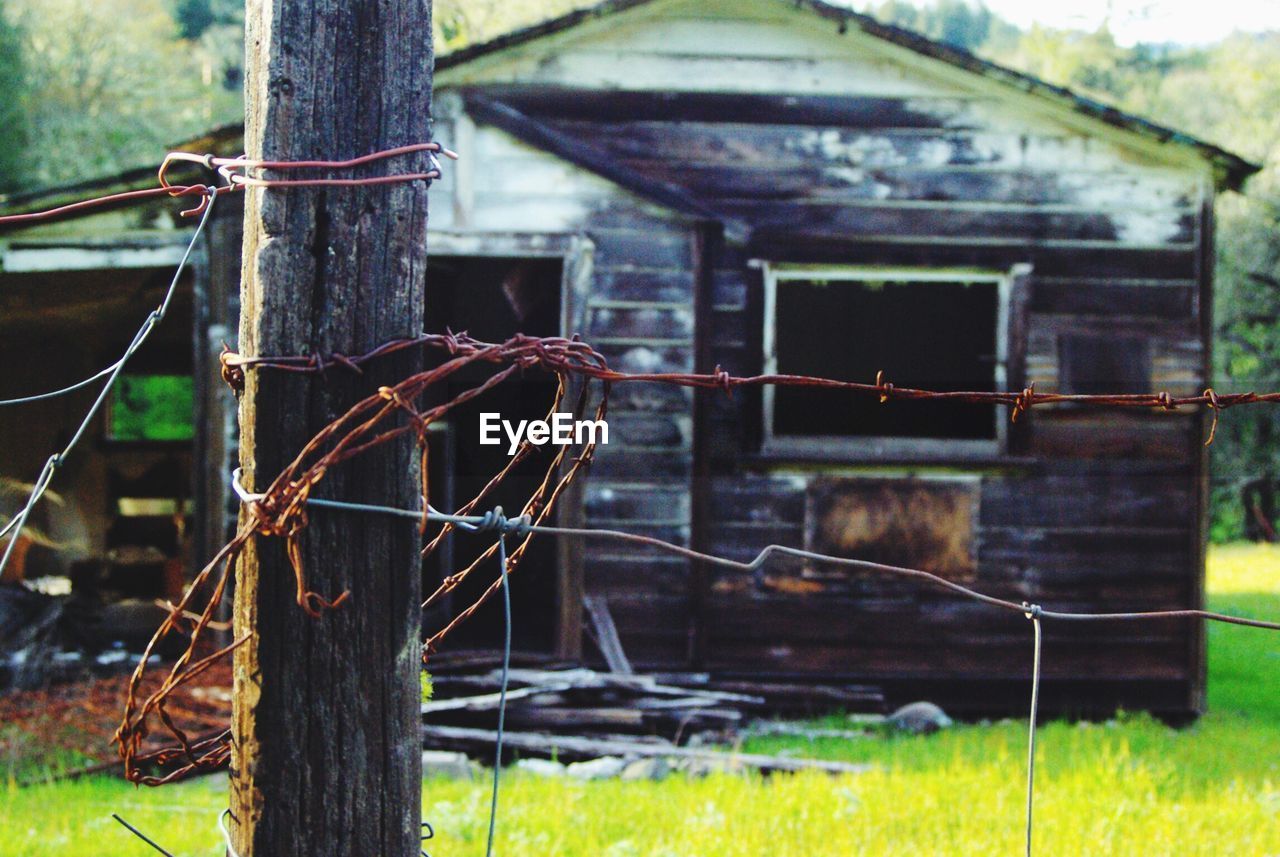 Barbed wire fence with abandoned hut in background