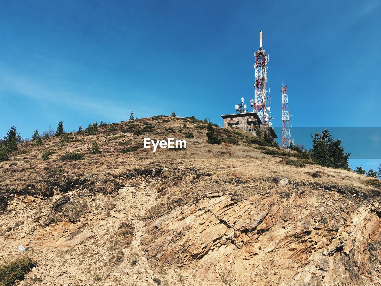 Low angle view of repeater towers on mountain against sky