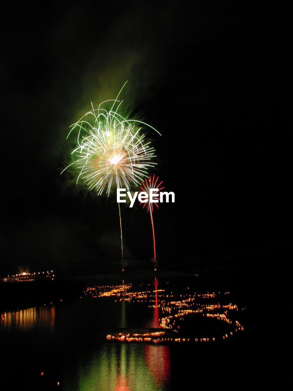 LOW ANGLE VIEW OF FIREWORK DISPLAY OVER RIVER AT NIGHT