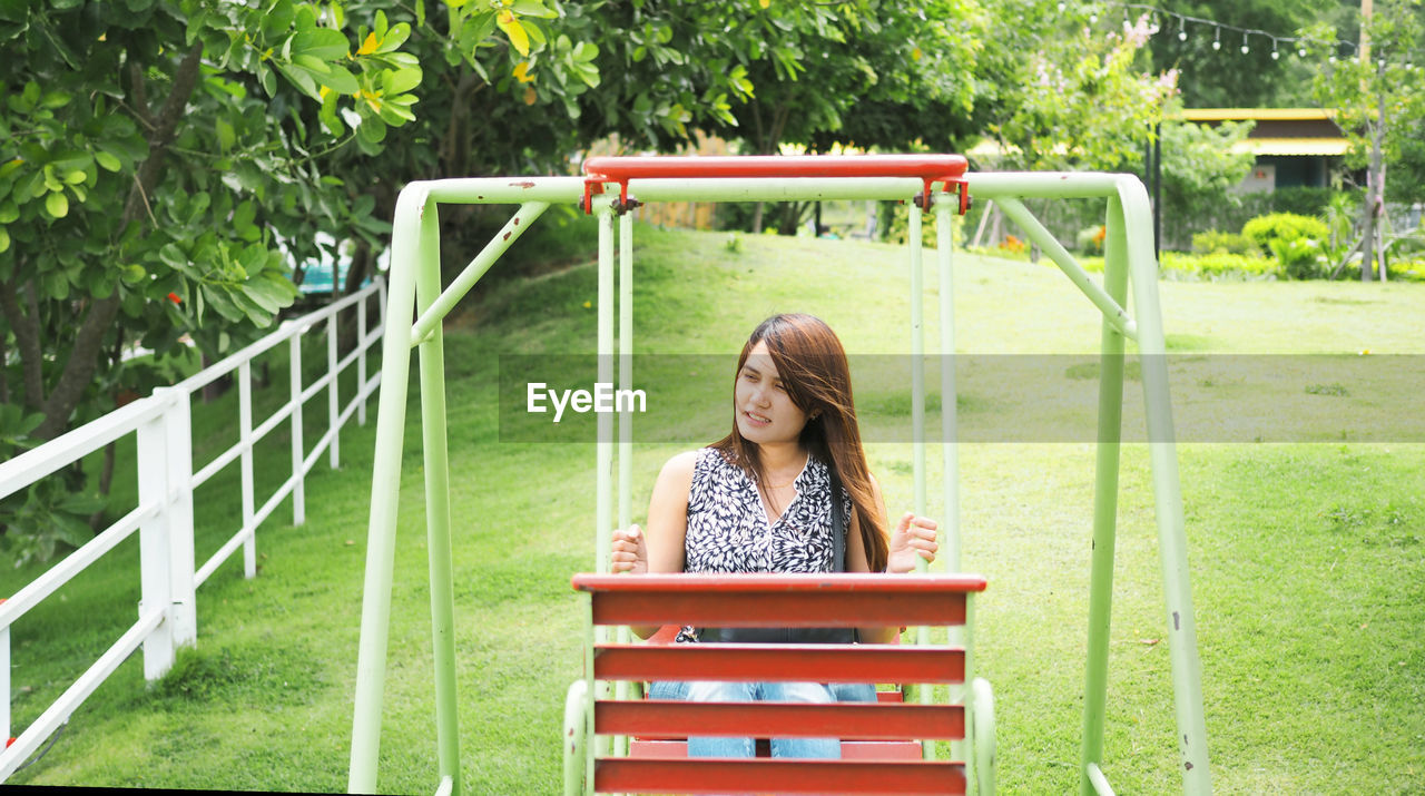 High angle view of mid adult woman swinging at park