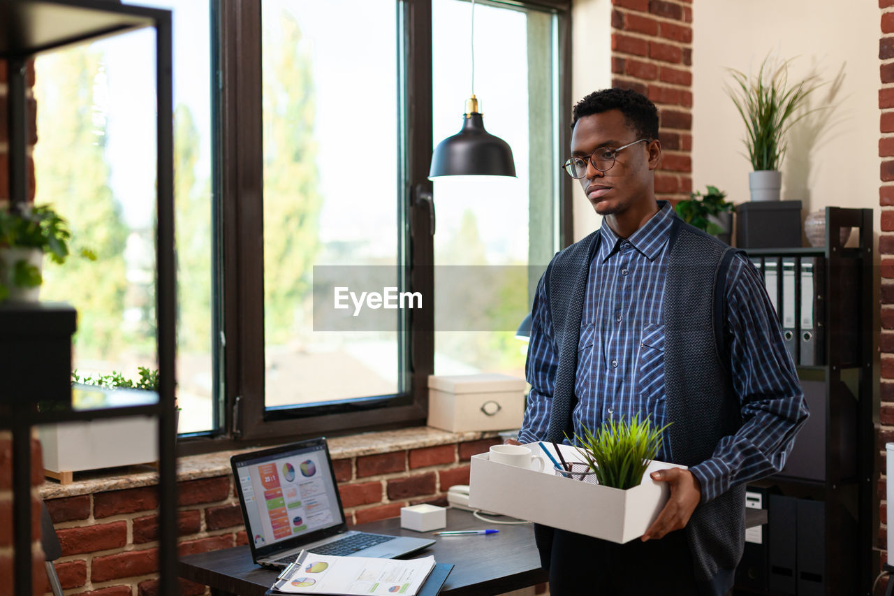 Sad businessman holding belongings at office